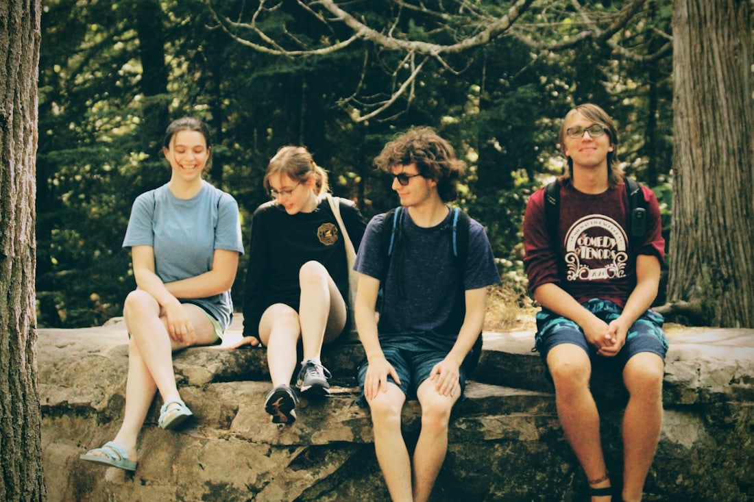 A group of young people sitting together outdoors and smiling